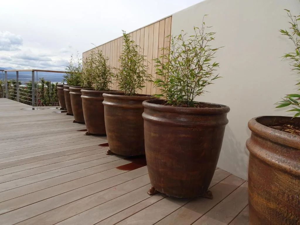 Wooden deck with terracotta planters and railing overlooking ocean view
