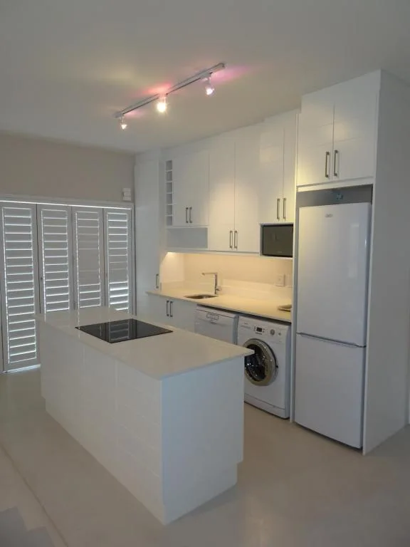 Modern kitchen with white cabinetry, island counter, and stainless steel appliances