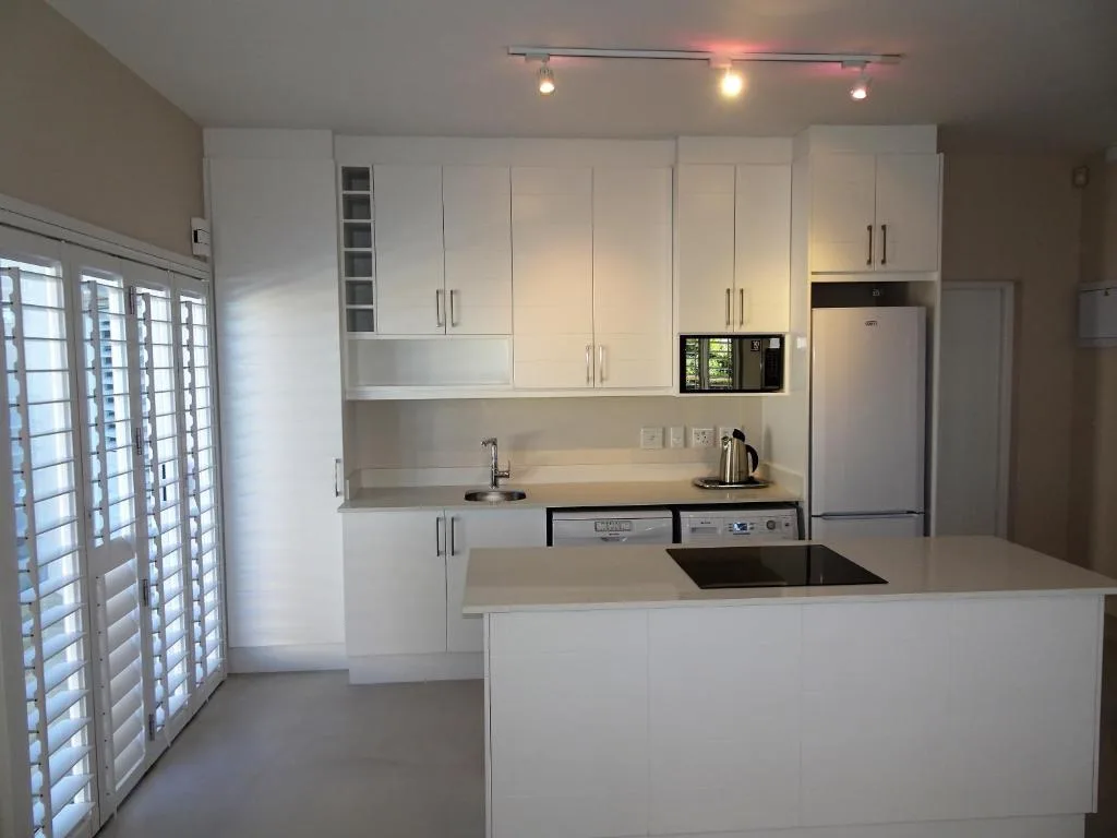 Modern white kitchen with island, stainless steel appliances, and ample cabinetry