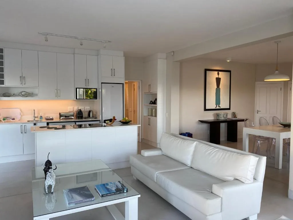 Open-plan living area with white sofa, kitchen, and modern decor throughout
