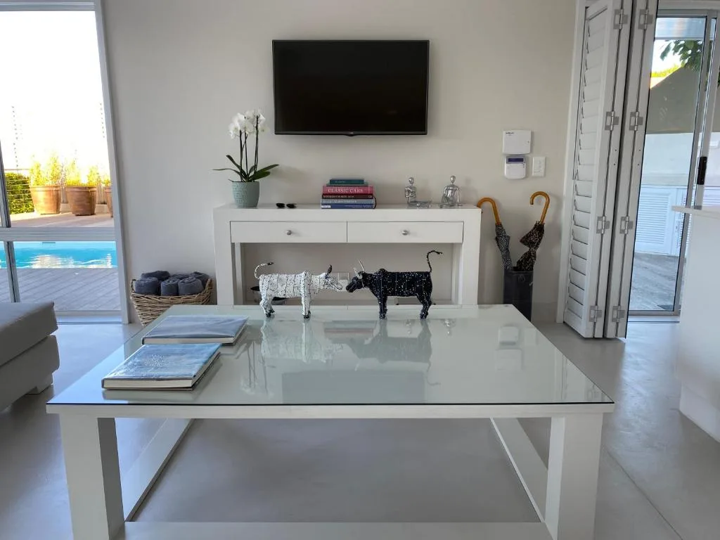 Bright lounge with wall-mounted TV, white console table, and pool view