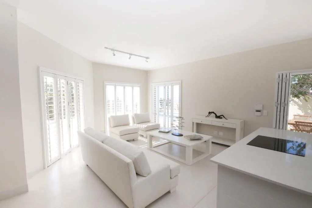 Bright modern lounge with cream sofas, white coffee table, and ocean views