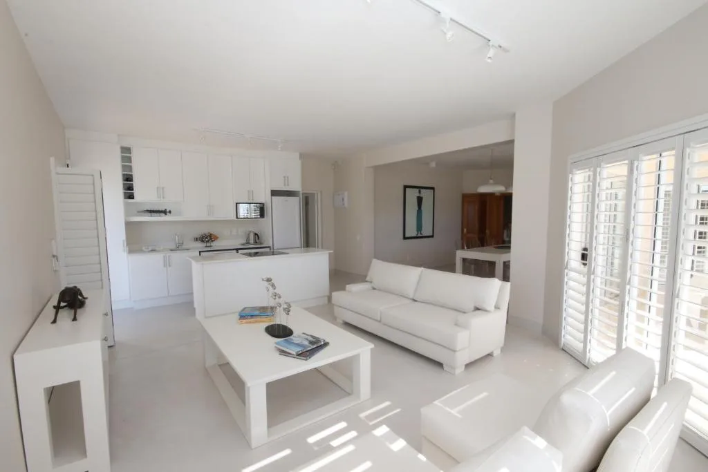 Bright modern lounge with white sofa, coffee table, and open kitchen