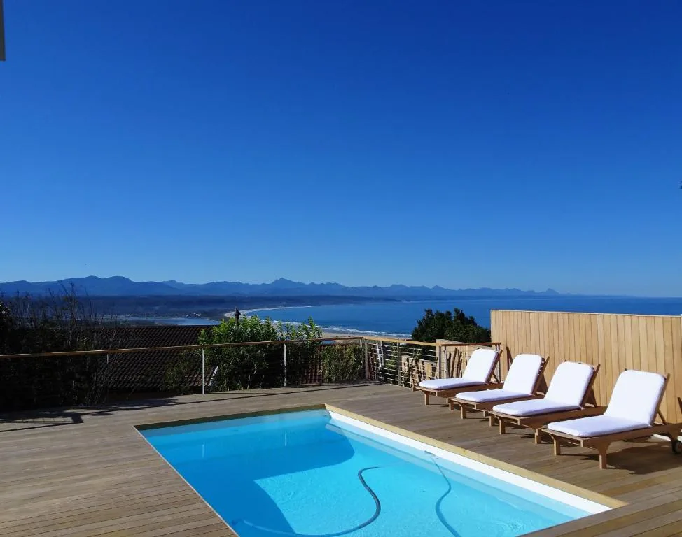 Swimming pool with loungers overlooking mountains and ocean views