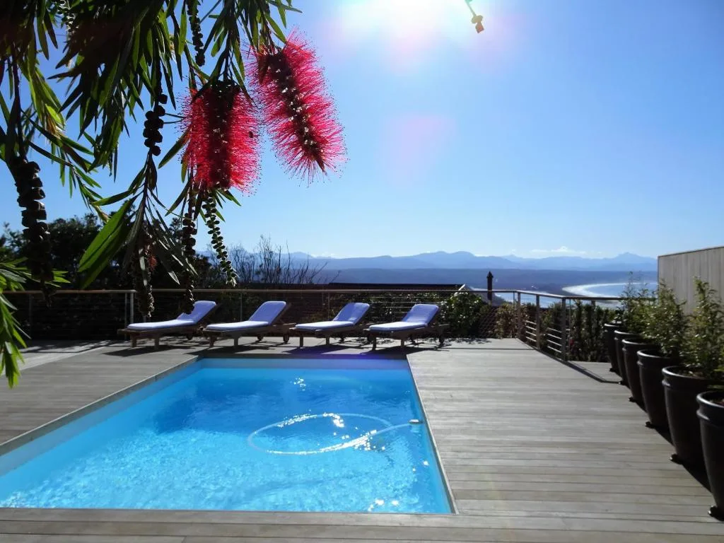 Swimming pool with lounge chairs overlooking lagoon and mountains