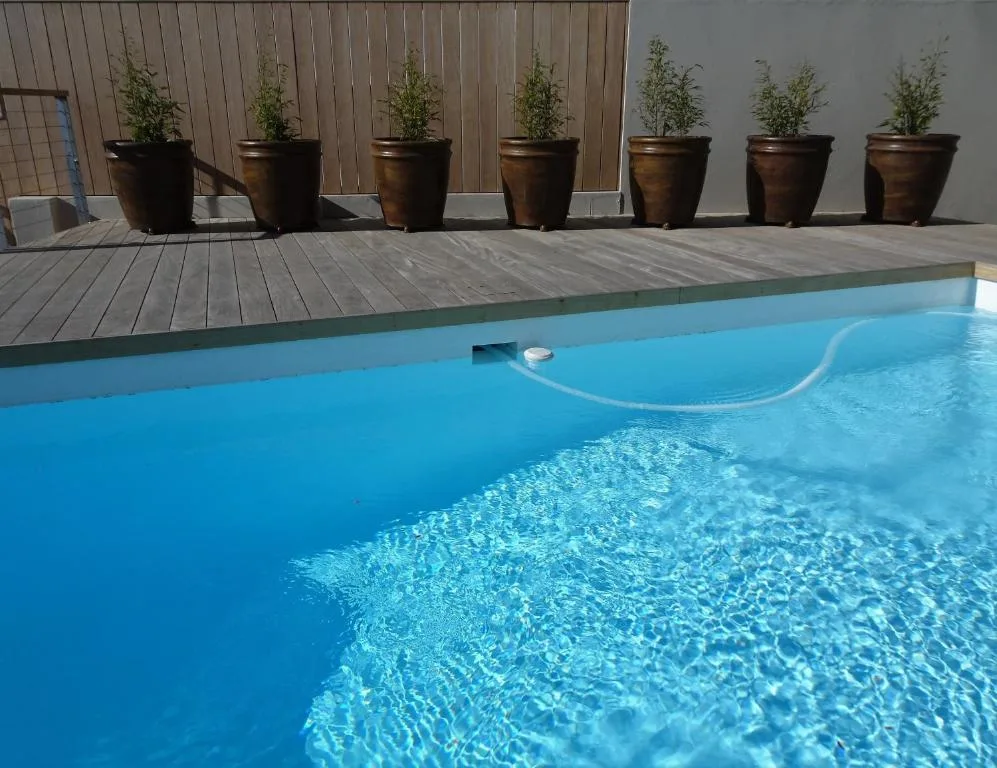 Clear blue swimming pool with wooden deck and potted plants nearby