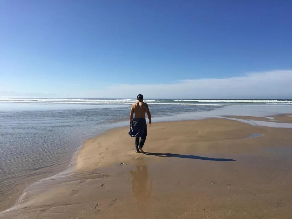 Wide sandy beach with calm waters and distant coastline under clear sky