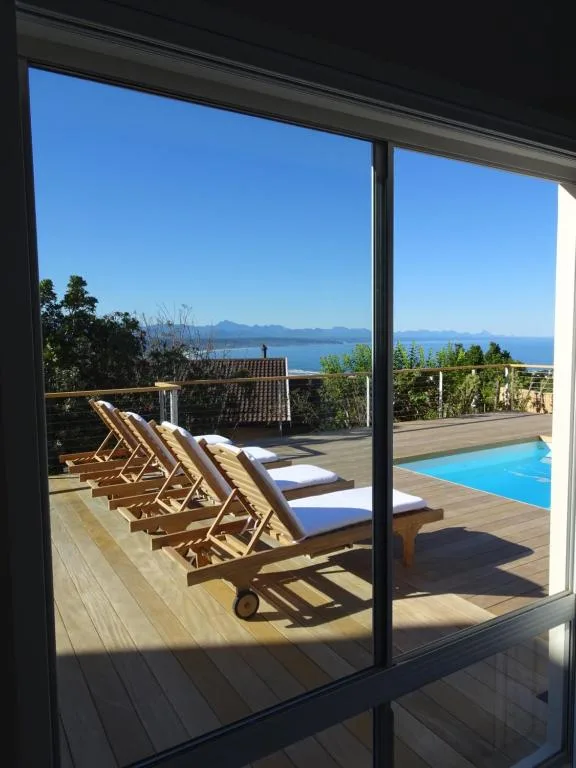 Mountain and ocean vista framed by large windows and deck loungers