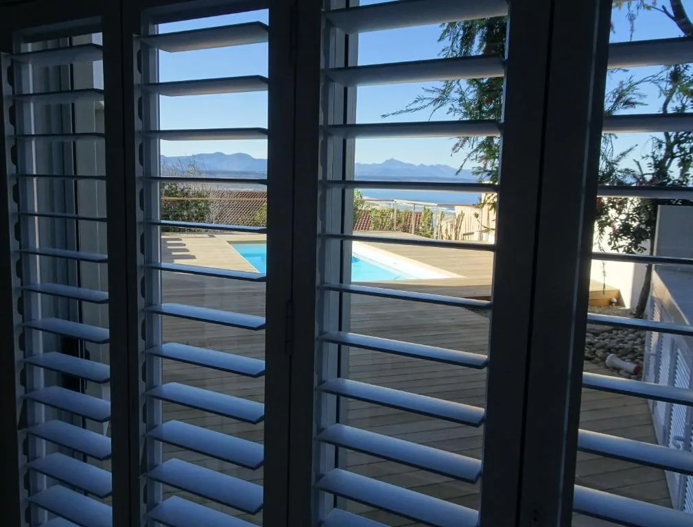 Ocean and mountain vista framed through louvered shutters and windows