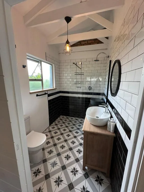 Modern bathroom with black and white subway tiles, patterned floor, vessel sink