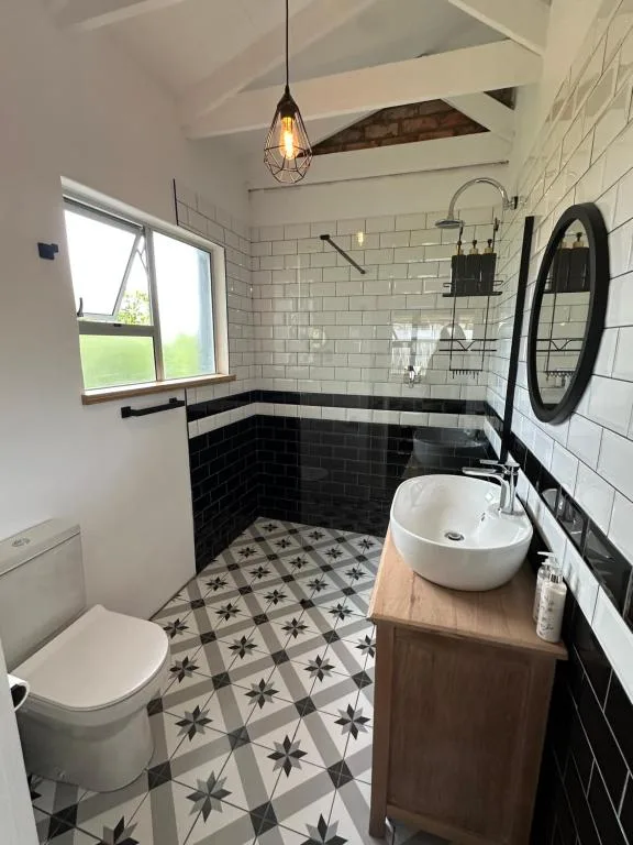 Modern bathroom with black and white subway tile, patterned floor, and round vessel sink