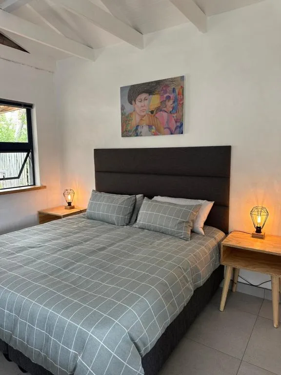 Modern bedroom with dark headboard, grid patterned bedding, and warm bedside lamps