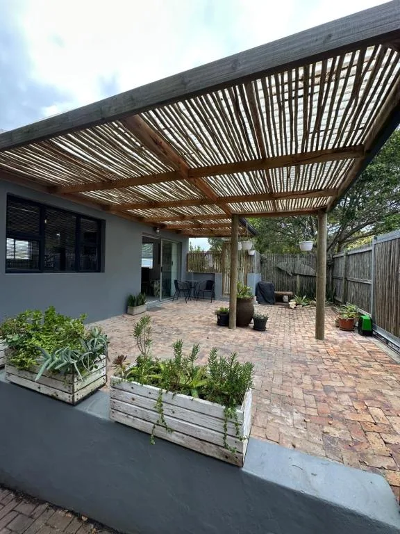 Spacious brick patio with slatted pergola, planters, and seating area