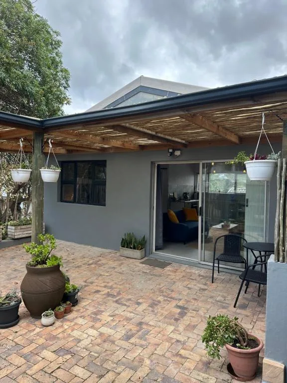 Covered outdoor patio with brick flooring, seating area, and potted plants