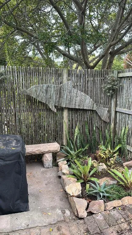 Rustic outdoor patio with wooden fencing, stone bench, and succulent plants