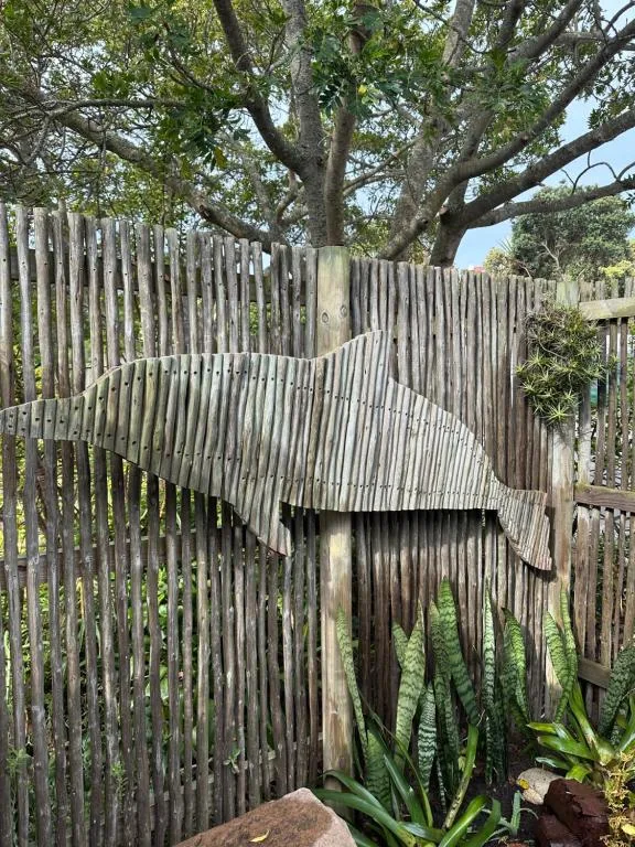 Wooden fence with artistic cutout of an elephant under tree