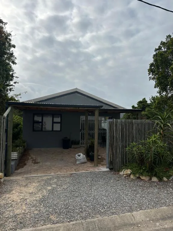 Dark grey modern studio building with covered entrance and gravel driveway