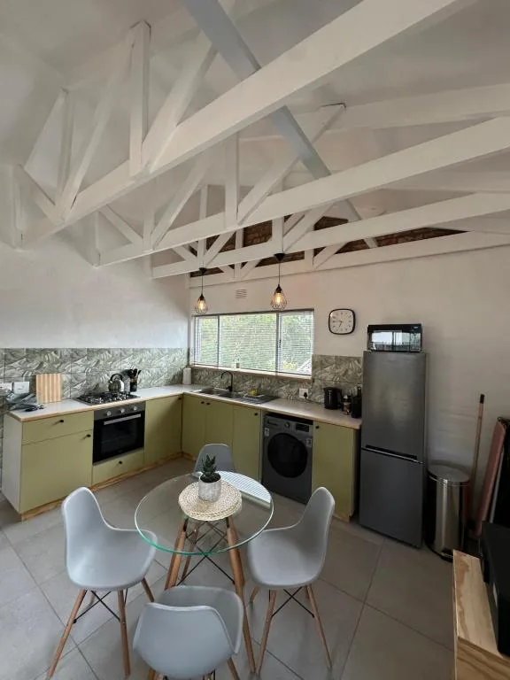 Modern kitchen with yellow cabinetry, exposed white beam ceiling, and dining table