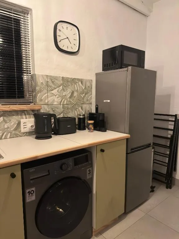Kitchen corner with refrigerator, washing machine, microwave, and kettle