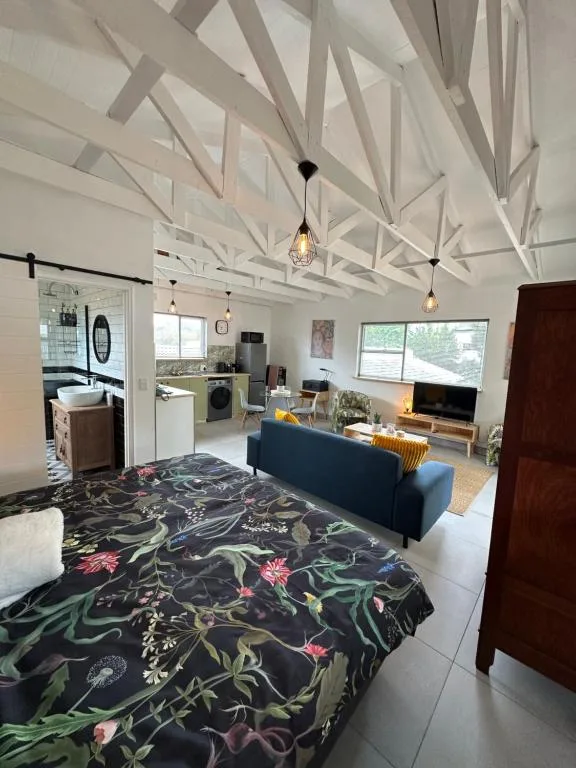 Open-plan living space with sofa, bed, kitchen and cathedral ceiling beams