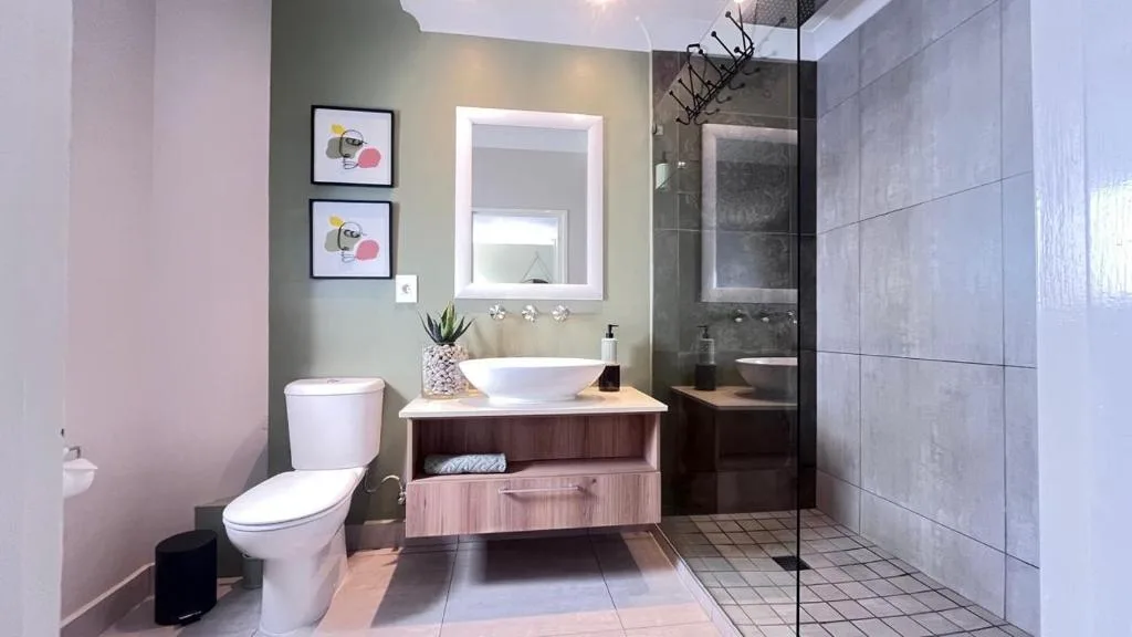 Modern bathroom with vanity sink, toilet, shower enclosure, and artwork