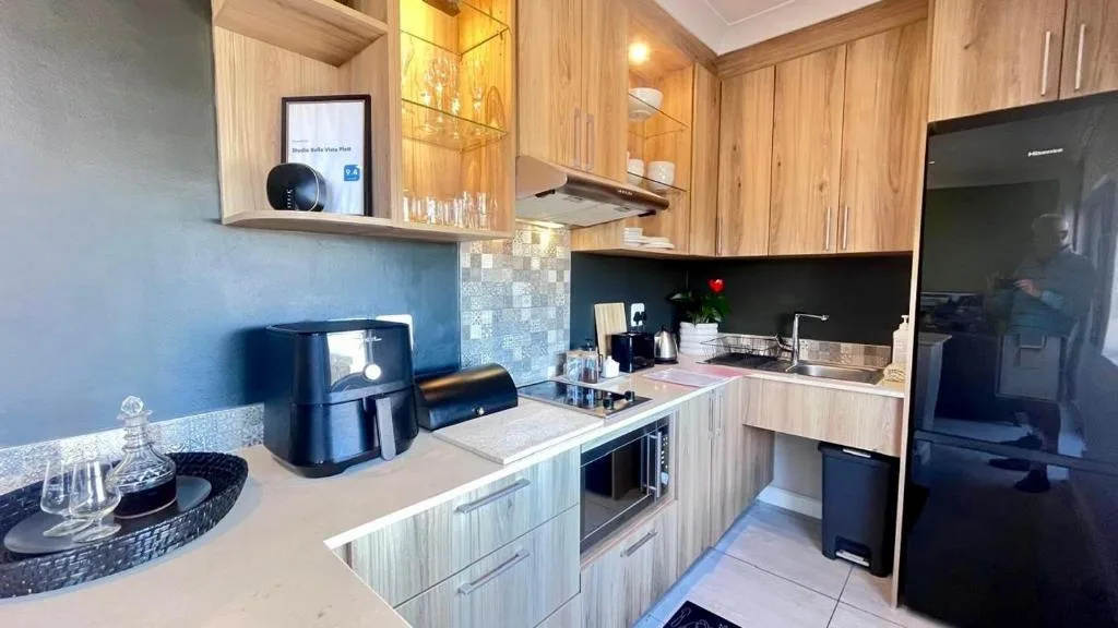Modern kitchen with light wood cabinetry, black countertop, and stainless steel appliances