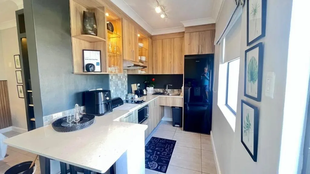 Modern kitchen with wooden cabinetry, black appliances, and white countertops