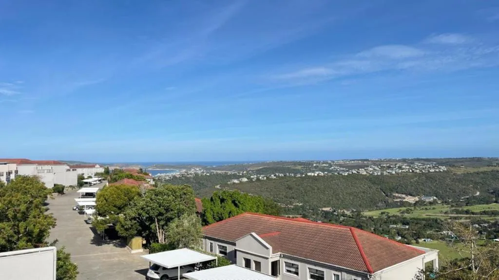 Expansive coastal landscape with lagoon, forested valleys, and distant ocean horizon