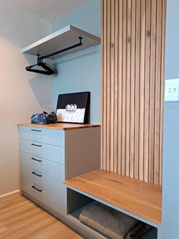 Modern bedroom corner with dresser, wooden bench, and wall-mounted clothing rack