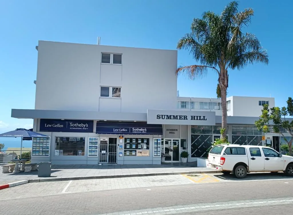 Modern white building facade with palm tree and street view