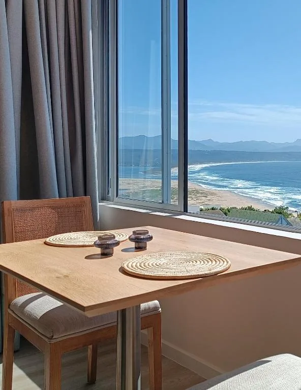Panoramic ocean and beach vista from dining area with mountain backdrop