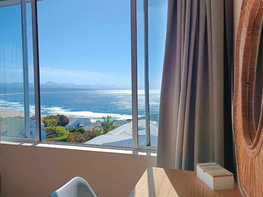 Expansive ocean and mountain views through large windows with drawn curtains