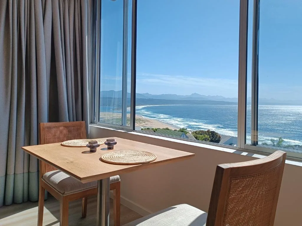 Dining table with ocean and mountain vista through floor-to-ceiling windows
