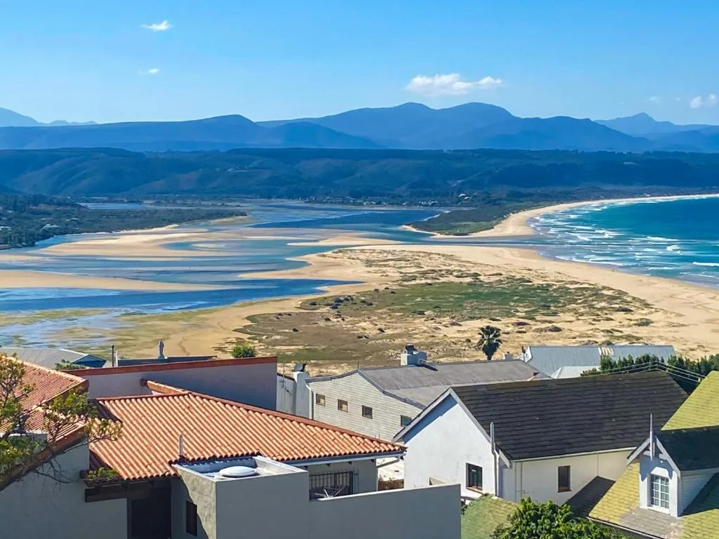 Coastal vista showing pristine beach, lagoon, mountains and property rooflines