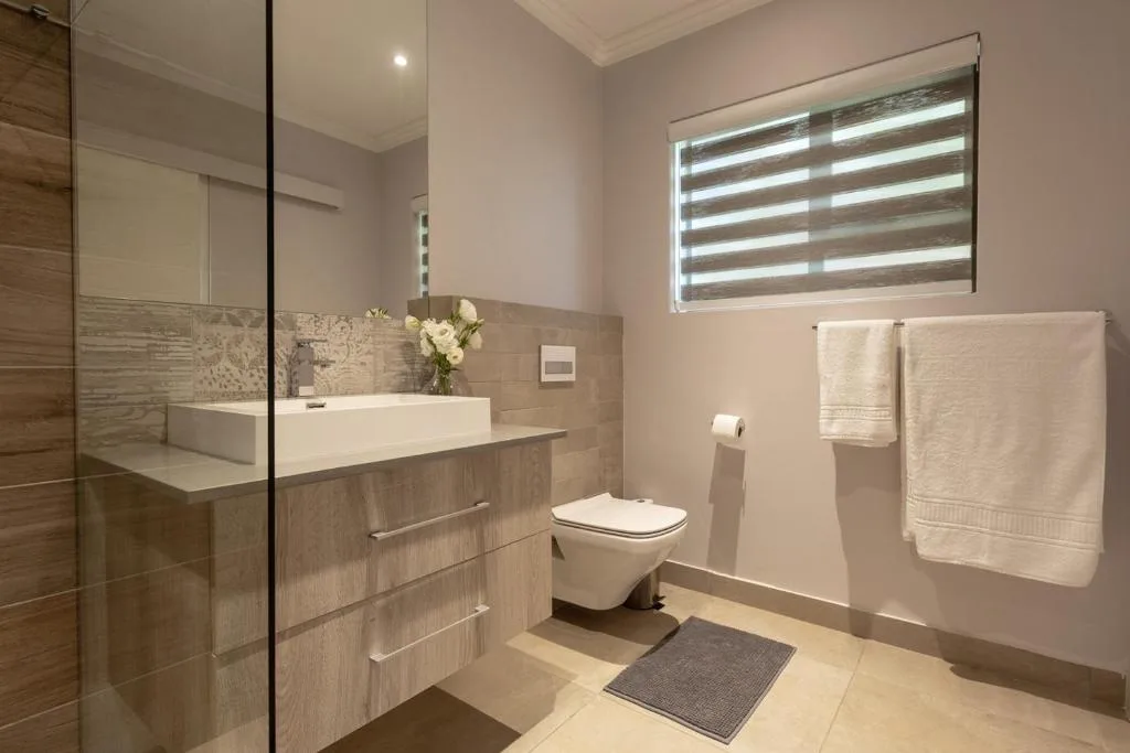 Modern bathroom with vanity, toilet, shower enclosure, and towel rails