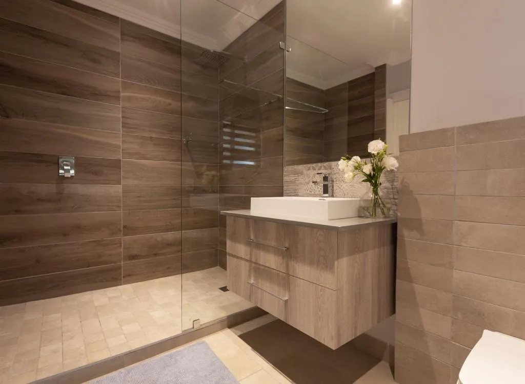 Modern bathroom with walk-in shower, wooden vanity, and white vessel sink