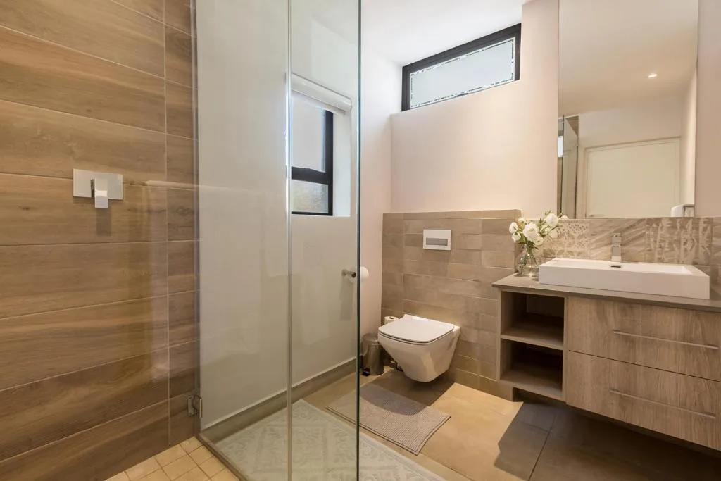 Modern bathroom with walk-in shower, toilet, and wooden vanity with sink