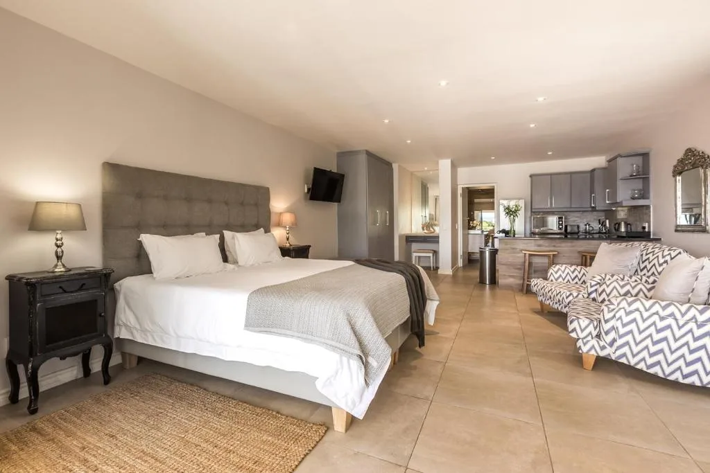 Spacious bedroom with king bed, lounge seating, and open-plan kitchen area