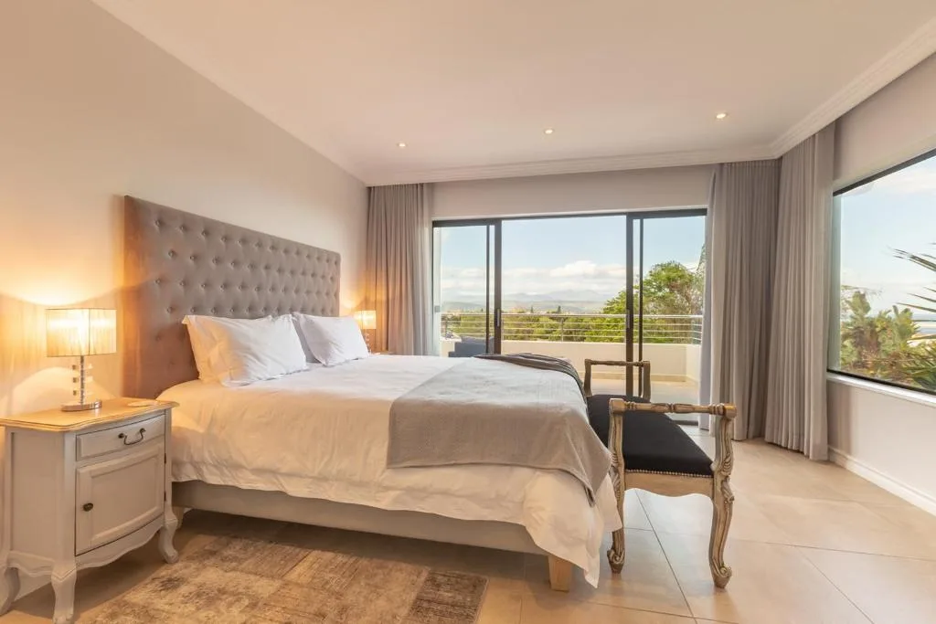 Bright bedroom with double bed, views across valley through glass doors