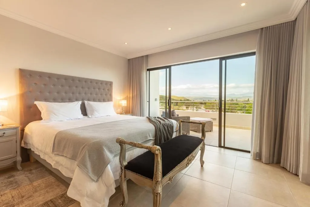 Luxury bedroom with king bed, large windows overlooking scenic valley landscape