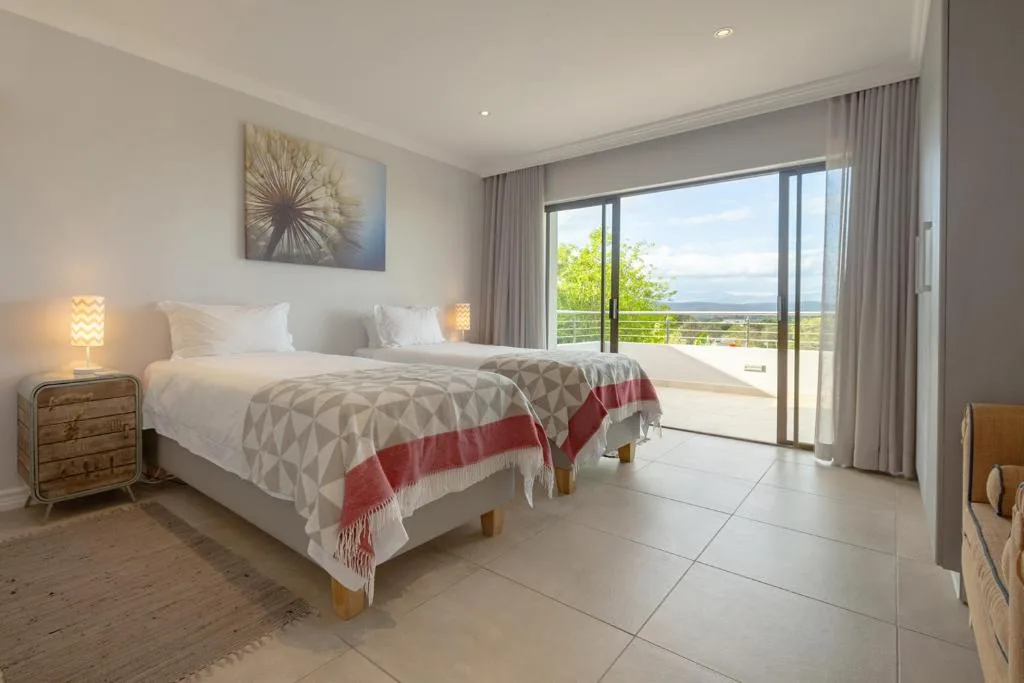 Bright bedroom with twin beds, ocean and mountain views through sliding doors