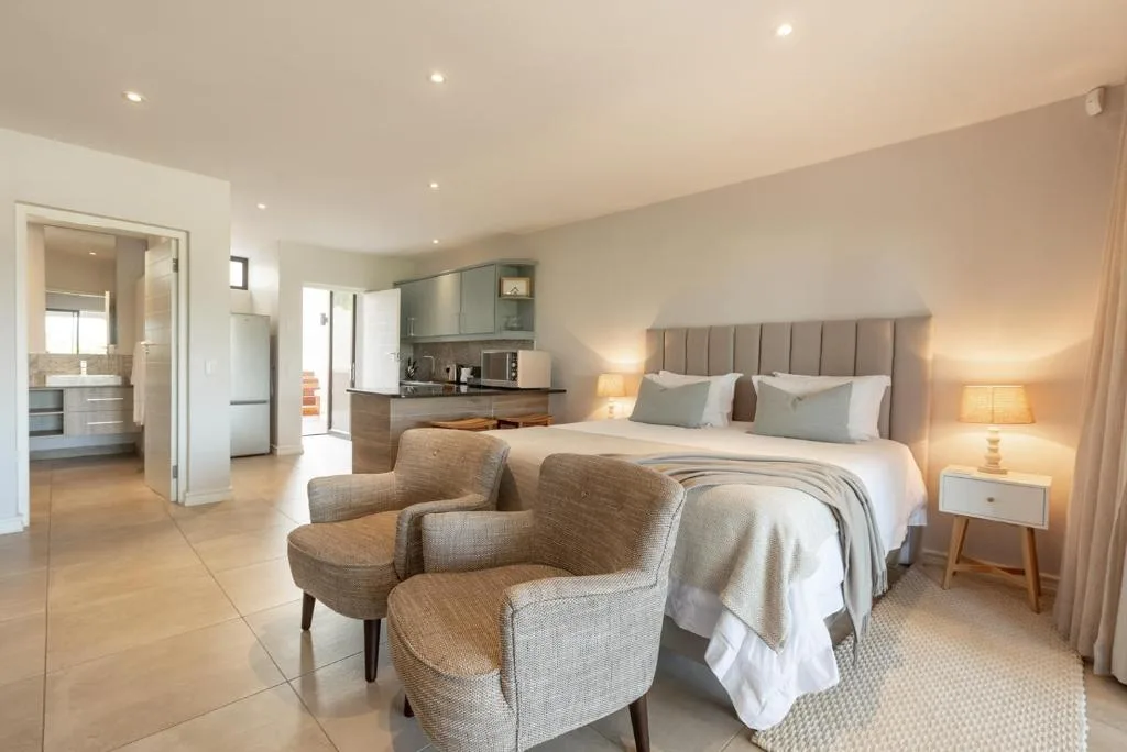 Spacious modern bedroom with king bed, upholstered headboard, and en-suite bathroom