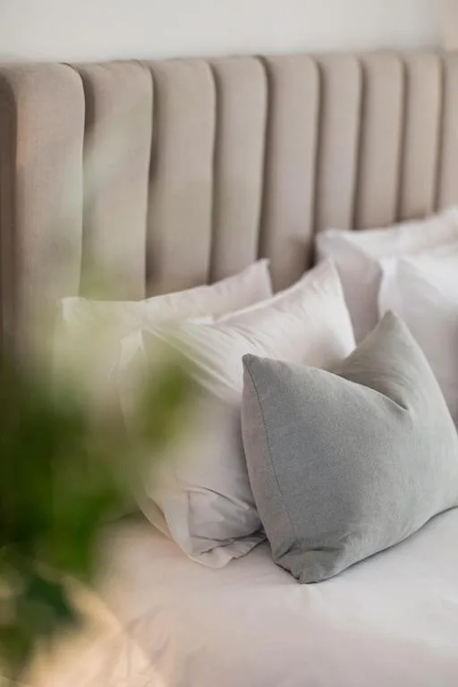 Bed with gray and white pillows against a soft upholstered headboard