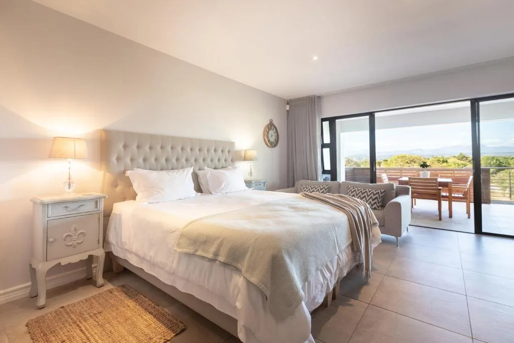 Spacious master bedroom with upholstered headboard and ocean view doors