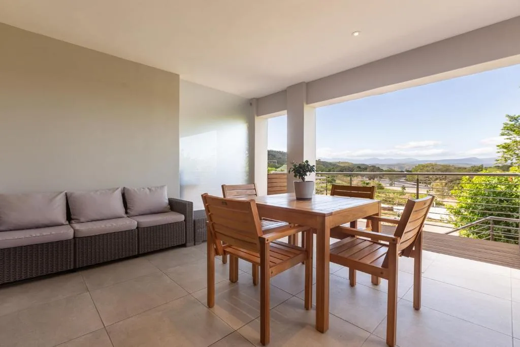 Spacious covered deck with dining table, lounge seating, and panoramic mountain views