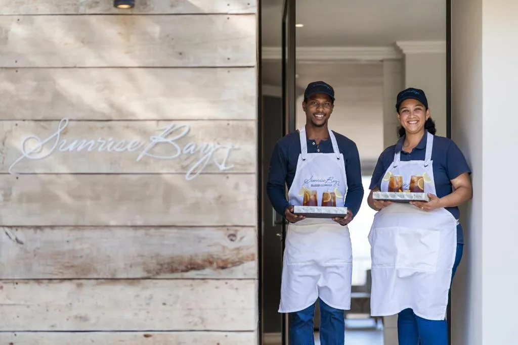 Smiling staff members at Sunrise Bay entrance with wooden signage