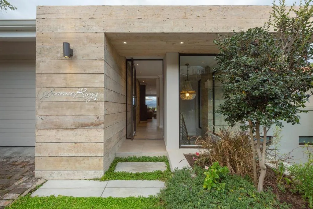 Modern stone entrance with glass doors and landscaped garden pathway