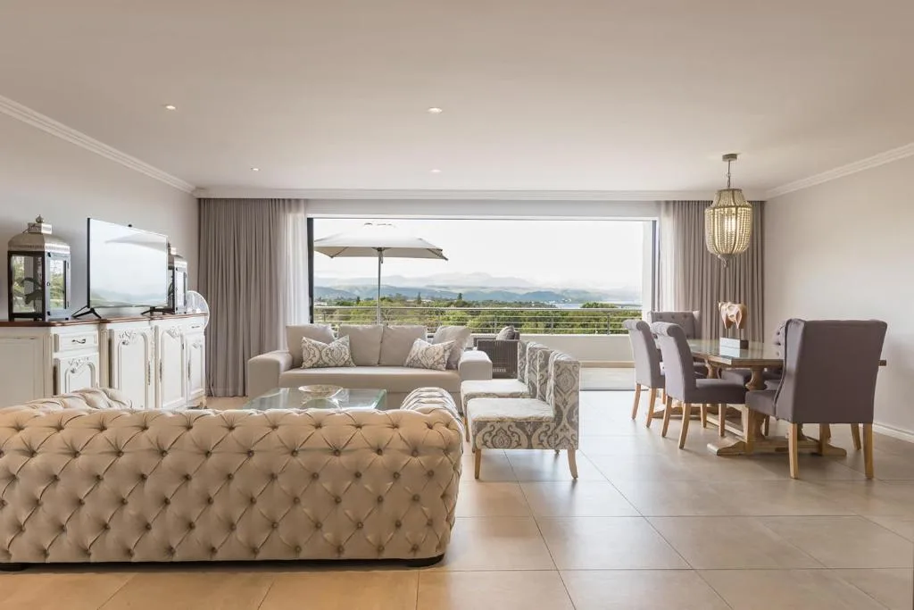 Spacious lounge with upholstered furniture and panoramic mountain views through large windows