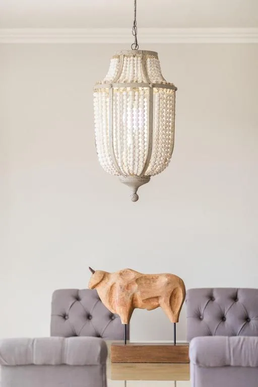 Modern lounge with beaded pendant light and sculptural wooden cow decoration