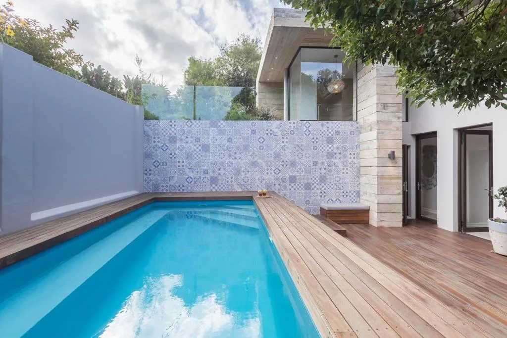 Modern swimming pool with wooden deck and contemporary architecture surrounding